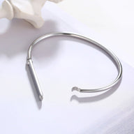 Bracelet jonc argenté en acier inoxydable avec plaque personnalisable au design épuré.