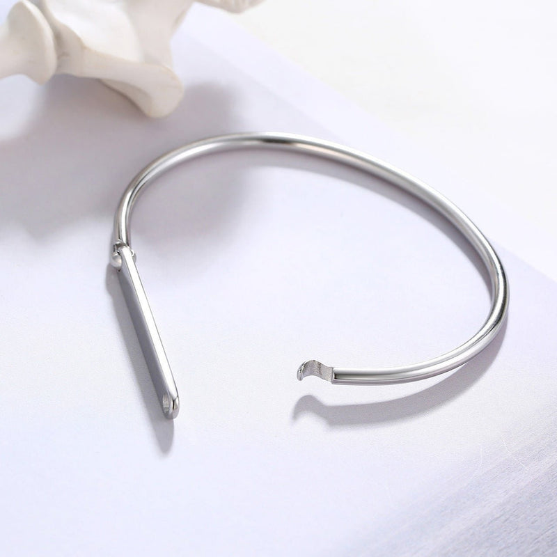 Bracelet jonc argenté en acier inoxydable avec plaque personnalisable au design épuré.