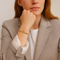 Bracelet jonc fin en acier inoxydable doré avec gravure personnalisée porté au poignet féminin.