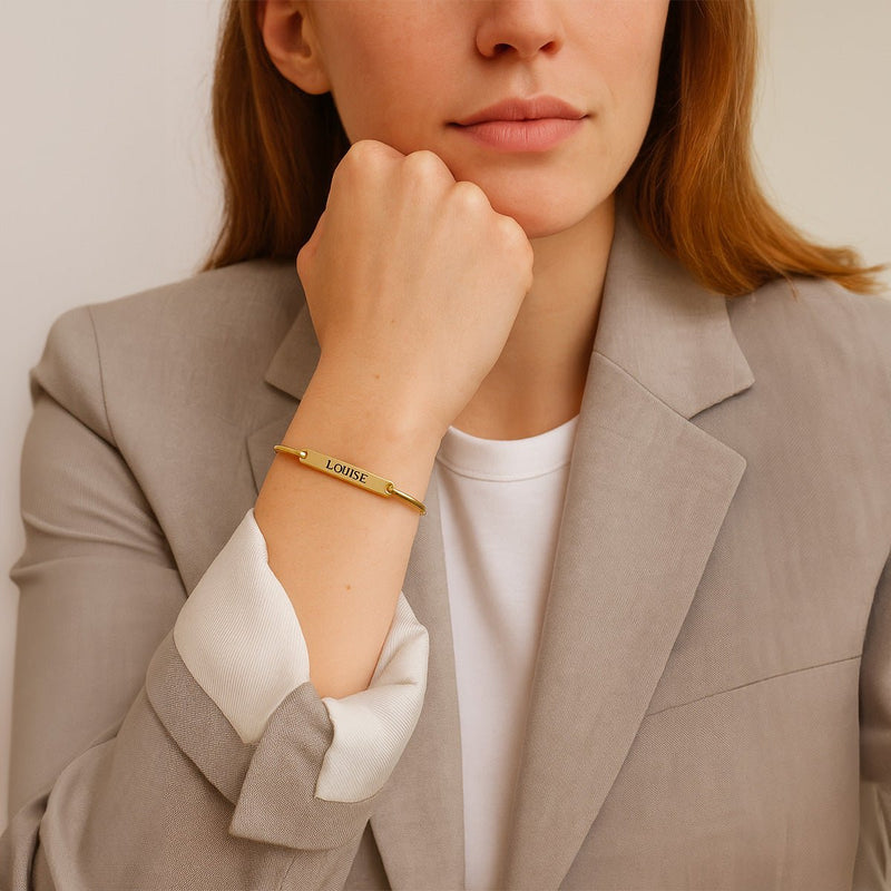 Bracelet jonc fin en acier inoxydable doré avec gravure personnalisée porté au poignet féminin.