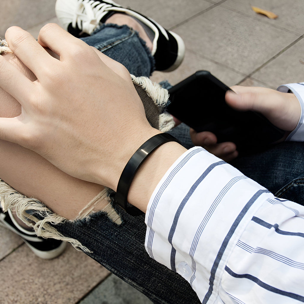 Bracelet jonc en acier inoxydable noir, design épuré pour homme, porté au poignet.