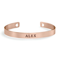 Bracelet jonc en or rosé avec gravure personnalisée "ALEX" et découpes cœur aux extrémités.