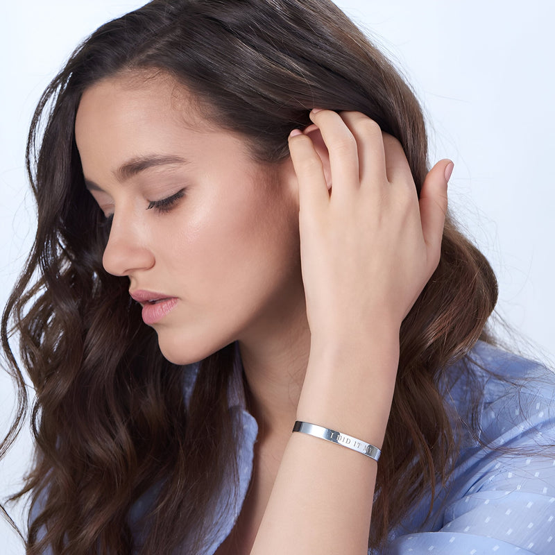 Bracelet jonc argent sterling lisse avec motifs cœur gravés porté au poignet.