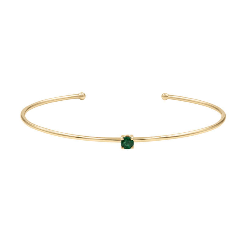 Bracelet jonc fin en acier doré avec petite pierre verte carrée centrale.
