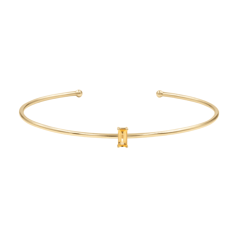 Bracelet jonc fin doré en acier inoxydable avec petite pierre rectangulaire jaune au centre.