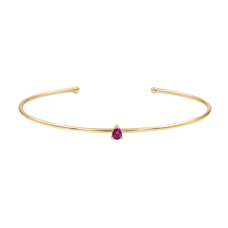 Bracelet jonc fin doré en acier inoxydable avec petite pierre rouge en forme de goutte au centre.