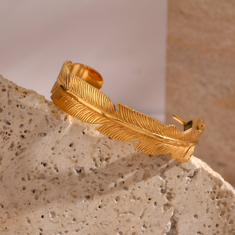 Bracelet jonc doré en acier inoxydable avec motif plume détaillé, style Dulcie.