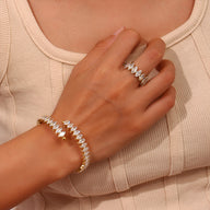 Bracelet jonc doré en acier inoxydable avec éclats scintillants porté au poignet féminin.