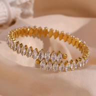 Bracelet jonc doré en acier inoxydable orné de pierres scintillantes ovales et rondes.