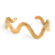 Bracelet jonc serpent en acier inoxydable doré avec texture martelée et silhouette ondulée.