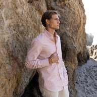 Bracelet jonc en titane noir au design crochet d'ancrage porté par un homme avec chemise rose pâle sur fond rocheux.