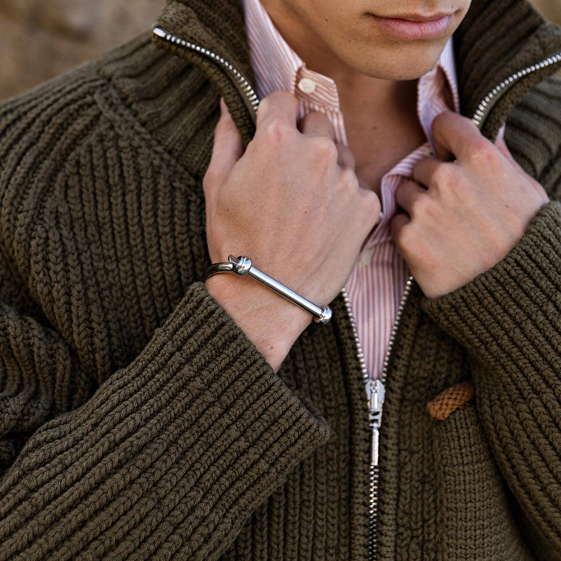 Bracelet jonc en titane argenté à design crochet d'ancrage porté au poignet masculin.