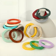Bracelets jonc irréguliers en résine, couleurs variées incluant orange, menthe, marron, jaune, vert et violet, style moderne .