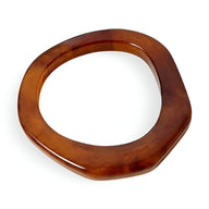 Bracelet jonc irrégulier en résine marron translucide avec finition lisse et forme organique.