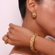 Bracelet jonc doré en acier inoxydable avec pierres vertes et blanches, porté avec bague assortie et boucle d’oreille créole .