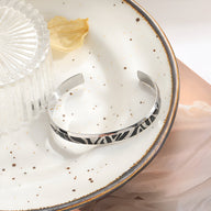 Bracelet jonc en titane argenté avec motif tigré noir, finition lisse et moderne.