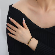 Bracelet jonc en titane or avec motif tigré porté au poignet, style élégant pour femme.