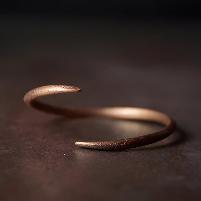 Bracelet jonc torsadé en cuivre vintage couleur marron avec finition mate et extrémités effilées.