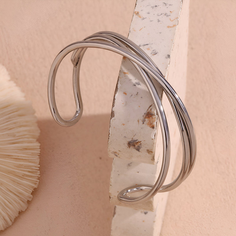 Bracelet jonc argenté en acier inoxydable avec design torsadé triple et finition lisse.