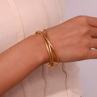 Bracelet jonc doré en acier inoxydable à triple torsade, design élégant et moderne.