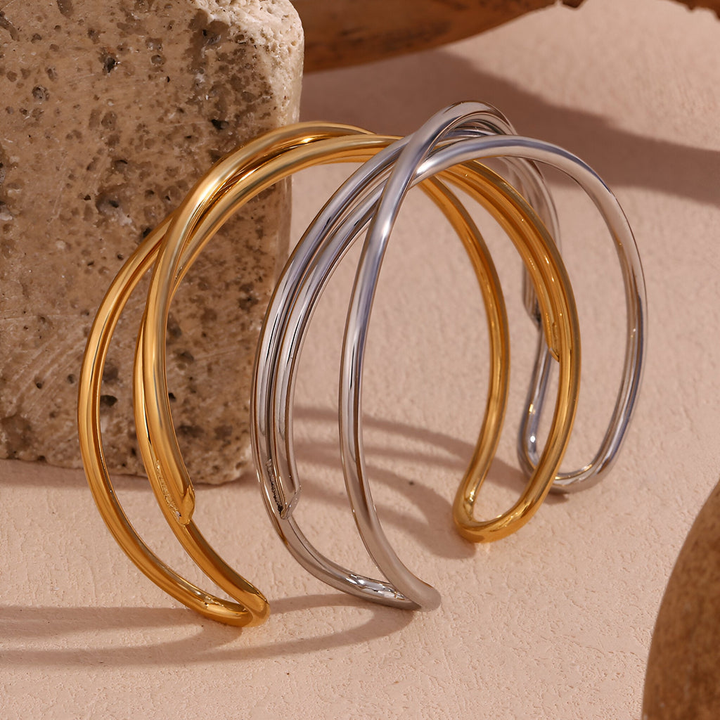 Bracelet jonc trio torsade en acier inoxydable, finition or et argent, design épuré et moderne.