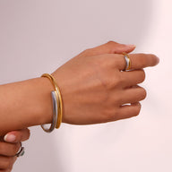 Bracelet jonc bicolore or et argent en acier inoxydable porté au poignet, design épuré et élégant.