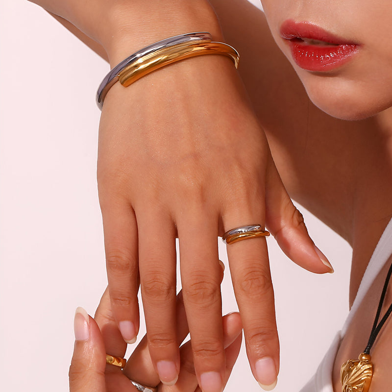 Bracelet jonc bicolore or et argent en acier inoxydable porté au poignet, style moderne et élégant.