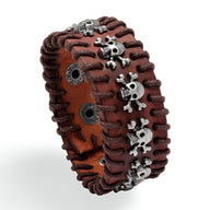 Bracelet large en cuir marron avec coutures en cuir foncé et têtes de mort métalliques argentées.