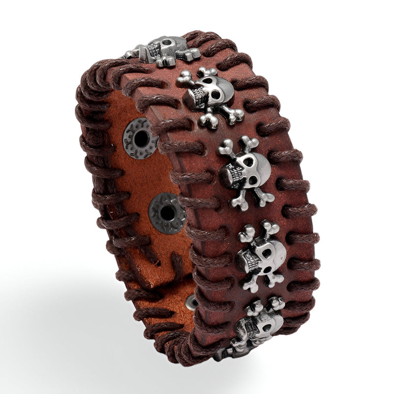 Bracelet large en cuir marron avec coutures en cuir foncé et têtes de mort métalliques argentées.