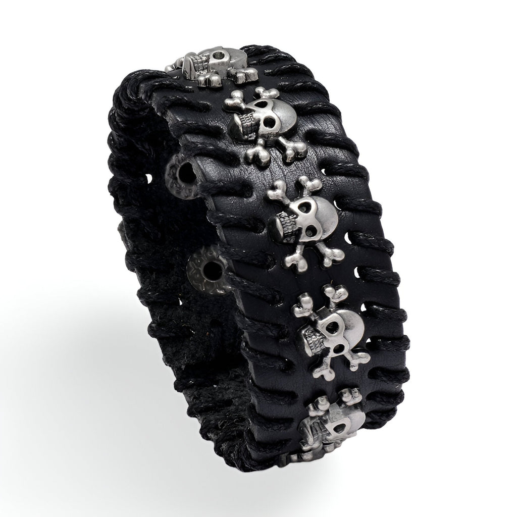 Bracelet large en cuir noir avec plusieurs têtes de mort argentées et couture apparente.