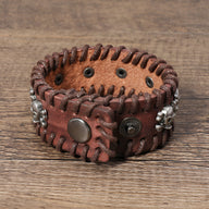 Bracelet large marron en cuir tressé, orné de plusieurs têtes de mort en métal argenté, style masculin.