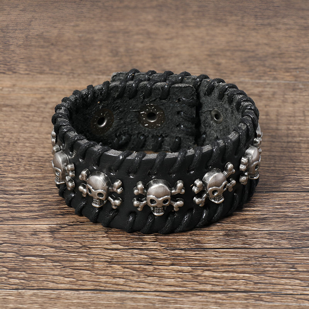 Bracelet large en cuir noir avec têtes de mort en métal argenté tissées sur toute la surface.