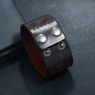 Bracelet large en cuir café avec motifs western gravés et fermoir à boutons pression en métal argenté.