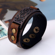 Bracelet large en cuir marron avec motif floral gravé, fermoir à boutons-pression en métal doré.