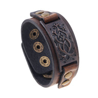 Bracelet large en cuir marron avec motif floral embossé et boutons-pression dorés.
