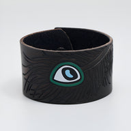 Bracelet large en cuir marron avec motif œil floral vert et noir gravé.