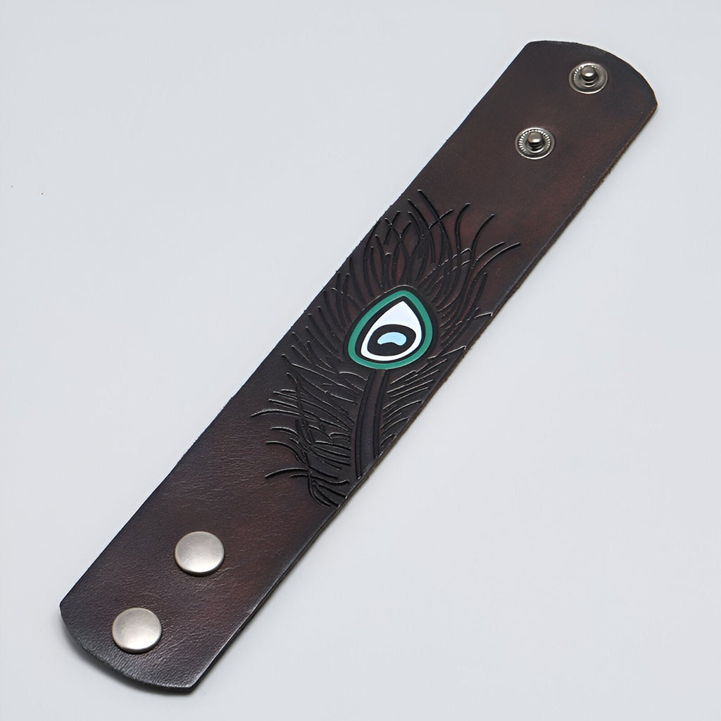 Bracelet large en cuir café avec motif œil floral embossé et fermoir à boutons-pression métalliques.