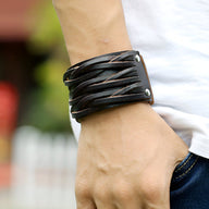 Bracelet large en cuir noir texturé, design original avec sangles croisées et rivets métalliques, style masculin.