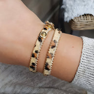 Bracelet léopard en microfibre marron avec bouton-pression doré et bordure en biais fin doré.