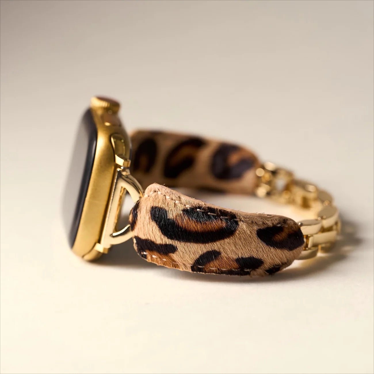 Bracelet pour Apple Watch motif léopard beige et noir, finitions dorées brillantes, texture poils souple.
