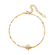Bracelet fin en or avec fleur de lotus centrale et perles multicolores délicates.