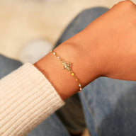 Bracelet fin en argent sterling doré avec pendentif lotus délicat sur poignet féminin.