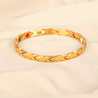 Bracelet magnétique en titane doré avec maillons incurvés et pastilles colorées au revers.