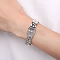 Bracelet magnétique en titane argenté avec croix chrétienne sur poignet homme.