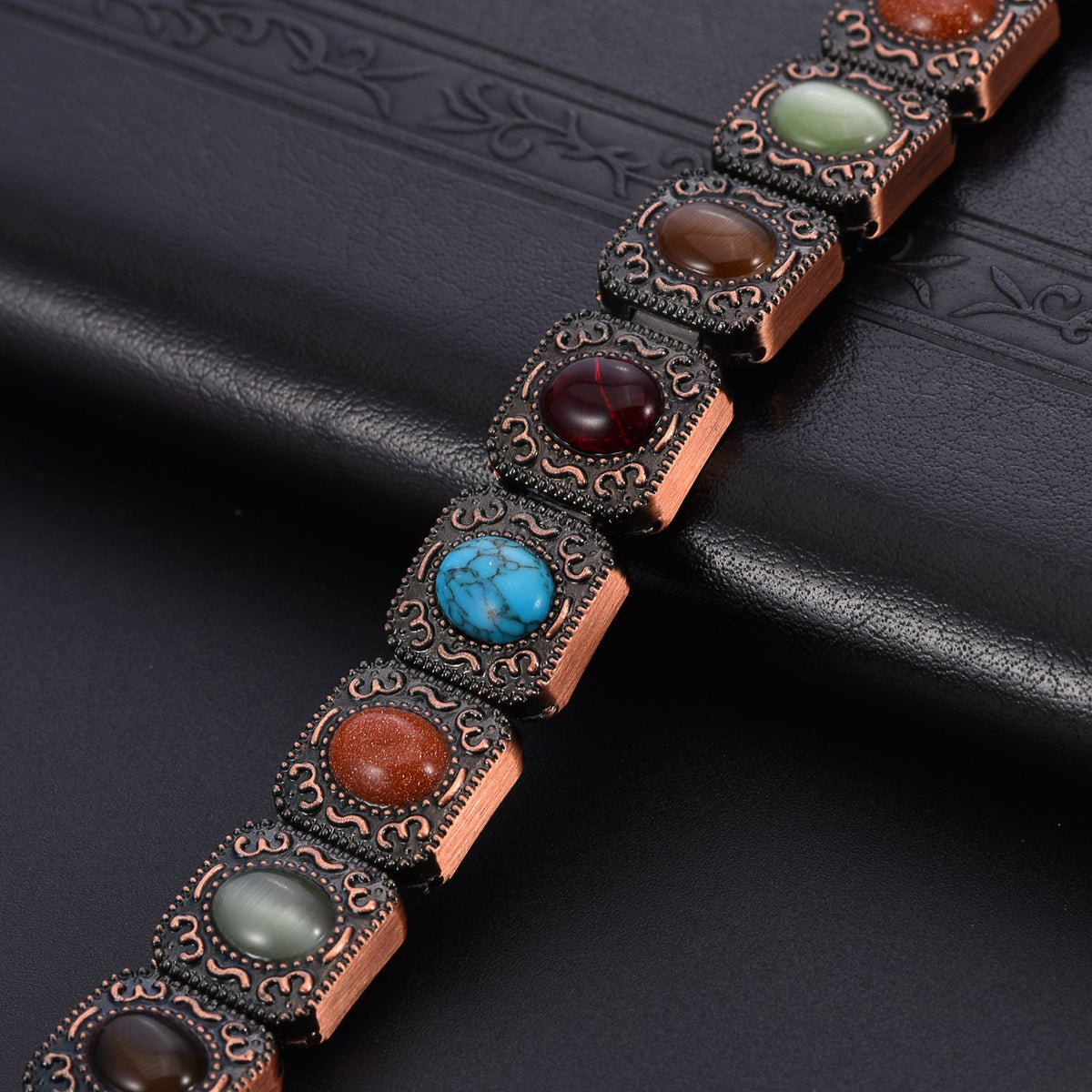 Bracelet en cuivre avec maillons rectangulaires ornés de pierres naturelles multicolores serties de détails gravés délicats.