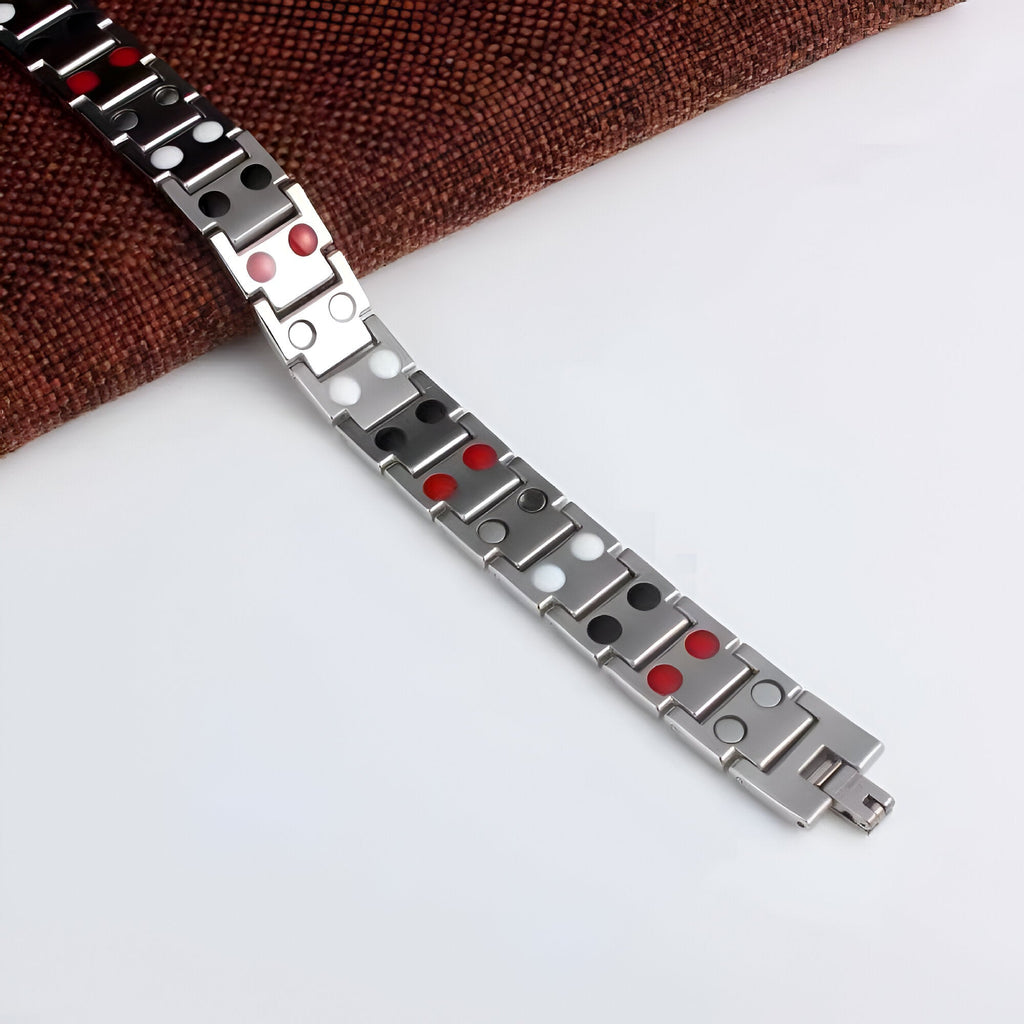 Bracelet magnétique homme en acier inoxydable argenté avec accents rouges intégrés.