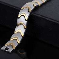 Bracelet magnétique homme en acier inoxydable argenté avec motifs dorés ondulés, modèle Haldor.