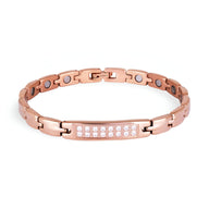 Bracelet magnétique femme en acier titane or rosé avec pierres blanches sur plaque centrale.