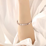Bracelet magnétique en acier titane or rosé pour femme avec détails texturés et fermoir élégant.