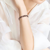 Bracelet magnétique en cuivre bronze tressé porté sur poignet de femme avec blouse blanche semi-transparente.